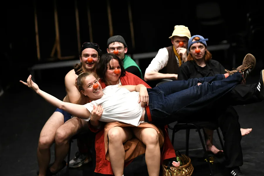 A smiling performer being carried by other members of the cast.