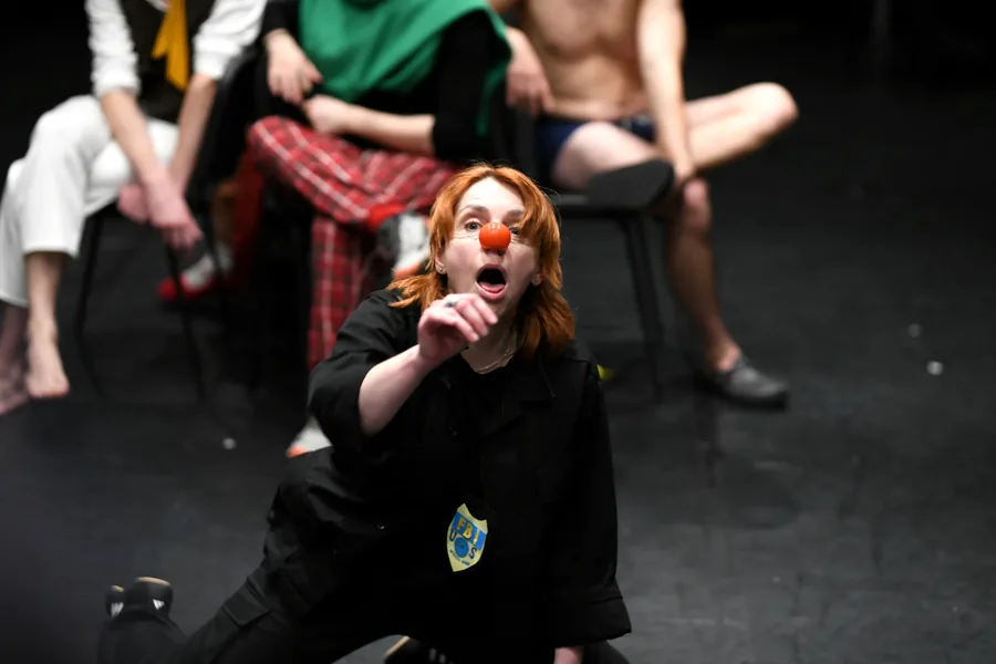 A performer in black with a red clown nose during the show.